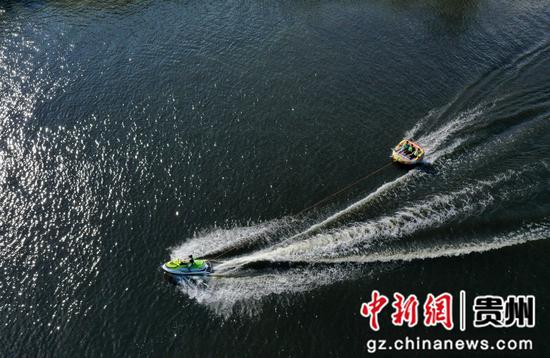 5月3日，人们在贵州省黔东南苗族侗族自治州丹寨县万达小镇景区湖面上驾驶快艇游玩。