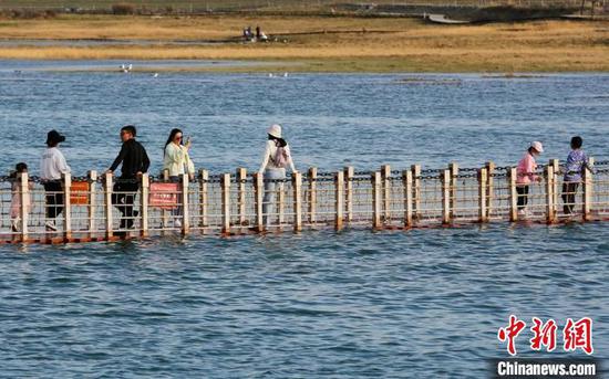 游人在巴里坤湖人工桥上拍照、赏景、休闲游玩。　达吾提·热夏提 摄