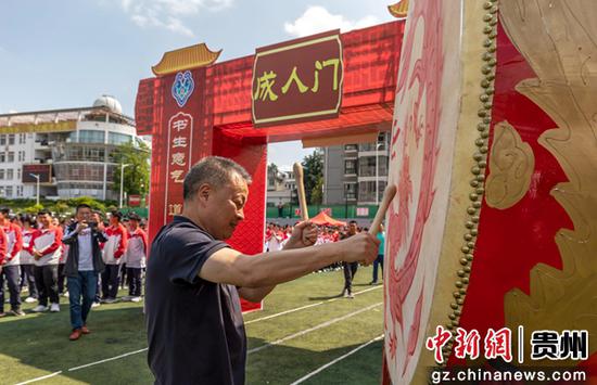 5月7日，贵州省黔西第一中学校长在2022届高三学生成人典礼上为学生击鼓。
