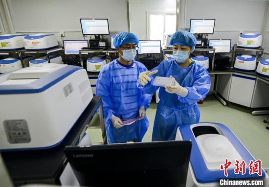 核酸实验室负责人李蕾(右)在核酸扩增区与同事一起忙碌。　刘新 摄