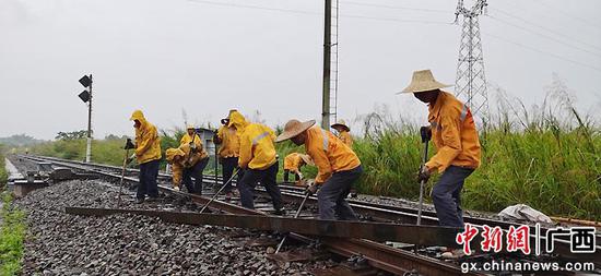 图为玉林工务段玉林三场工区职工在风雨中齐心协力进行拨出伤损钢轨作业。李慕传 摄