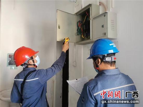 用电检查人员对扶绥县教育局配电室低压开关进行测温。黄薇 摄