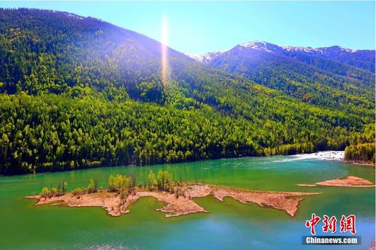 2022年5月21日，新疆喀纳斯景区风光。新疆阿勒泰地区喀纳斯湖是国家AAAAA级旅游景区，位于新疆维吾尔自治区阿勒泰地区布尔津县北部，其自然生态景观和人文景观始终保持着原始风貌。喀纳斯湖四周群山环抱、峰峦叠嶂，森林密布、草场繁茂，峰顶银装素裹，湖面碧波荡漾，群山倒映湖中，景色如画。中新社发 石晓坤 摄 图片来源：Cnsphoto