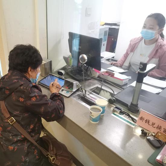 图为5月14日，塔城农商银行营业部柜员王雪纯<右>为高阿姨办理取款业务。 柴姣姣 摄