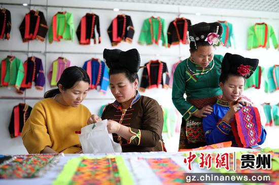 5月25日，苗族妇女在贵州省丹寨县金泉街道移民安置社区非遗手工坊交流刺绣技艺。