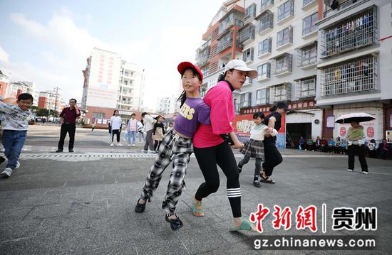 5月29日，家长与小孩子在贵州省丹寨县金泉街道移民安置社区参加背靠背运球赛跑活动。