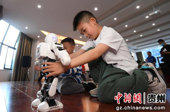 5月31日，一名小朋友在贵阳市南明区遵义路街道开展的“趣味科普 共享端午”主题活动现场与机器人互动。
