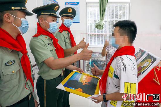孩子们将自己的绘画作品赠送给武警官兵。黄若贤 杨星 奎子清  供图