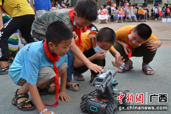 池鹏村委小学学生充满好奇地与智能机器人互动。潘雨茜 摄