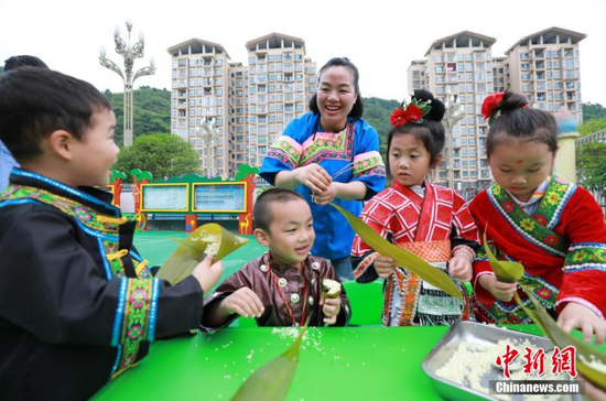 图为剑河县幸福社区中心幼儿园，家长在教孩子包粽子。 杨家孟 摄