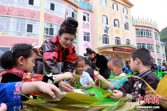 图为剑河县幸福社区中心幼儿园，家长在教孩子包粽子。 吴昌连 摄