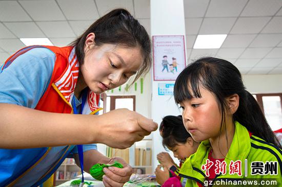6月2日，贵州省黔西市锦绣花都易地扶贫搬迁安置点，社会工作站工作人员指导搬迁群众的孩子手工制作龙舟。