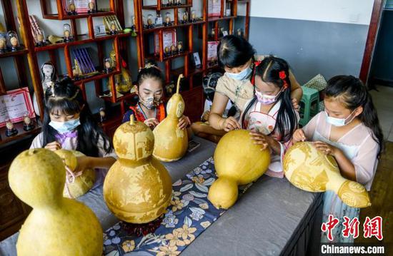几位小学生在葫芦雕刻代表性传承人马江红的指导下，学习葫芦雕刻技艺。　刘新 摄