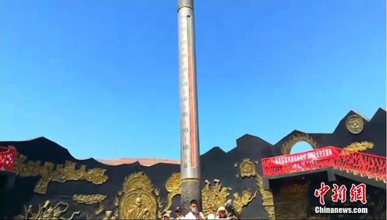 6月13日，吐鲁番市火焰山景区内巨型“金箍棒”电子温度计显示温度高达80摄氏度，吸引游客们争相上前与之合影。陈学敏　摄