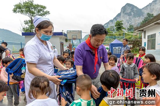 贵州省黔西市中医医院领导和医务人员给学生发放书包文具。