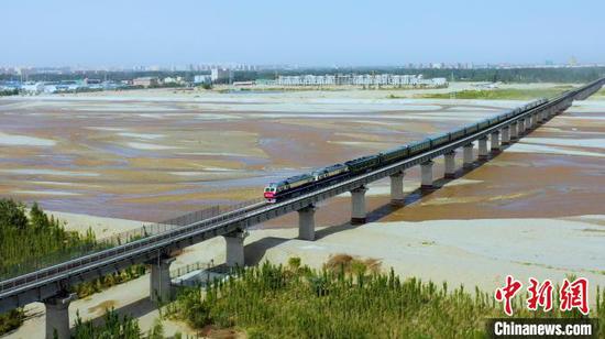 16日上午，和若铁路开通运营，首发列车穿过和田玉龙喀什河。　穆合塔尔 摄