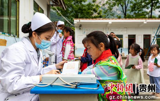 6月16日，贵州省黔西市中医医院医务人员在屯江教学点给学生做健康检查。