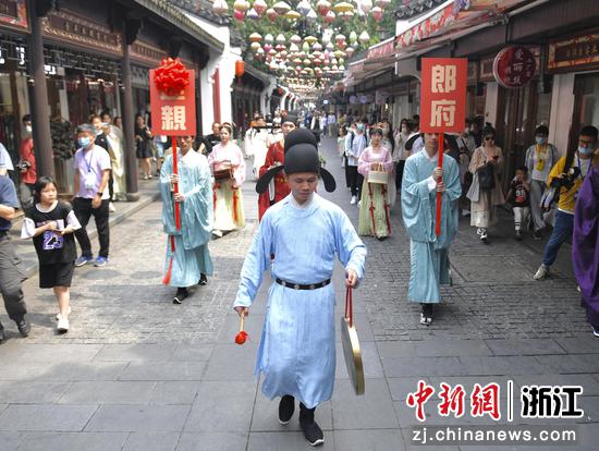 身着古装的“迎亲队伍”行走在杭州中国丝绸城步行街中。 王刚供图