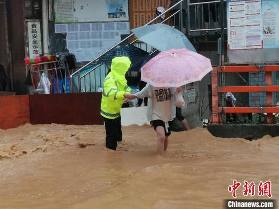 黔东南州局地遭特大暴雨袭击，交警搀扶民众过马路。　黔东南交警供图
