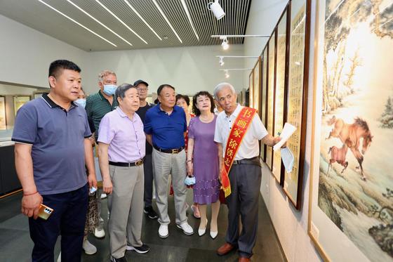 徐铁志在展览现场向爱新觉罗·毓峋等来宾介绍作品。