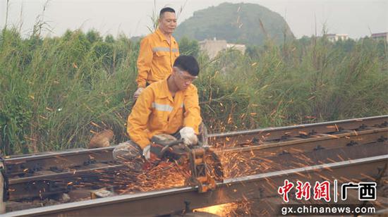 图为玉林工务段职工在上烤下热的线路上进行切割伤轨作业。谭人云摄