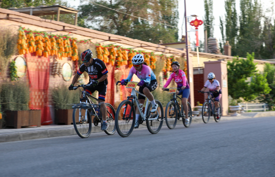 7月2日，第二届“人保财险杯”环罗布淖尔自行车拉力赛中，赛手穿过古勒巴格村。李晗摄