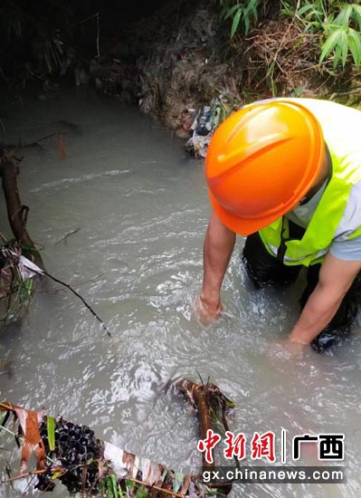 广西移动玉林分公司的抢修人员在陆川县涉水拉线缆。