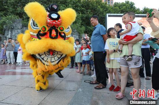 赖翊凡(狮头)与李洪江配合在县城诗乡广场练习舞狮吸引市民观看。　瞿宏伦 摄