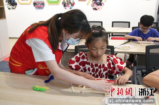 实践团成员教小学生编织技艺。 张虹 摄