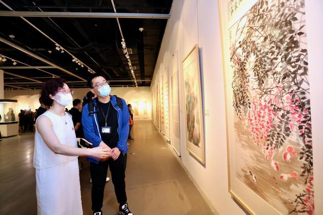 天津市群艺馆美术干部朱珊在展览现场介绍作品。