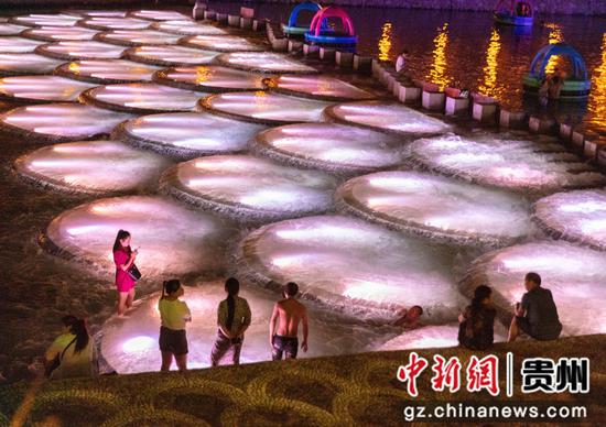 2022年7月16日，贵州省黔东南苗族侗族自治州施秉县杉木河夜漂景区灯火辉煌，流光溢彩，游客们在游玩度假，娱乐打卡。磨桂宾 摄