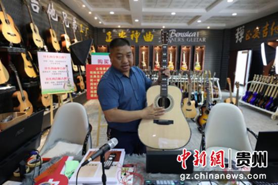 图为神曲吉他制造厂董事长郑传玖介绍正安吉他。