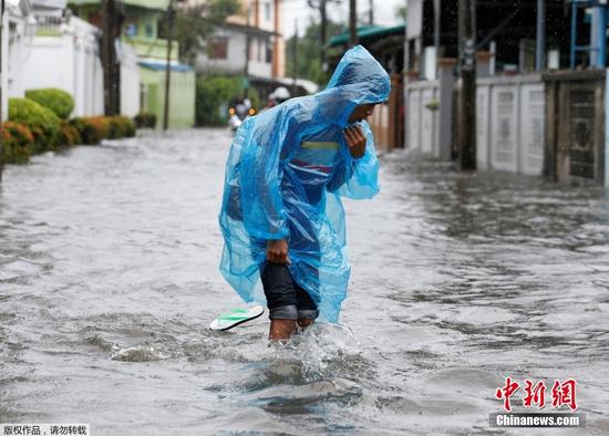 当地时间7月21日，泰国曼谷因近日出现持续性强降雨，多个区域内的单日降水量创下数十年来最高纪录，导致城市内涝严重，居民涉水出行。图为在被洪水淹没的道路上，行人蹚水前进。