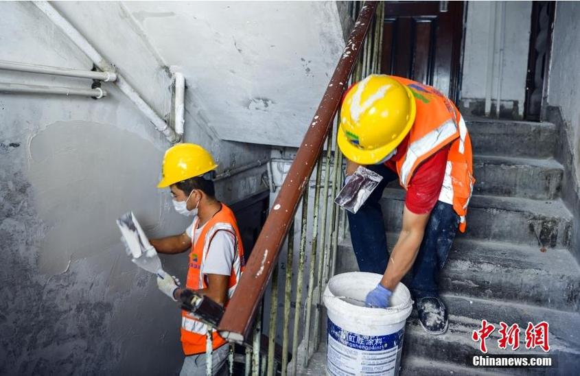 7月25日，新疆乌鲁木齐市沙依巴克区昆仑小区，工作人员正在修补楼梯间墙面。中新社记者 刘新 摄