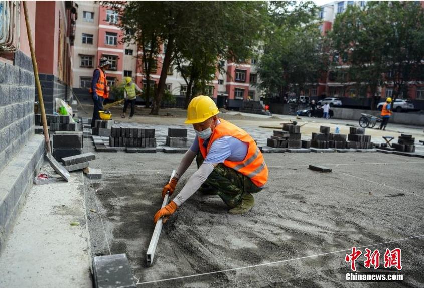 7月25日，新疆乌鲁木齐市沙依巴克区新通小区，工作人员正在小区空地铺设地砖。中新社记者 刘新 摄