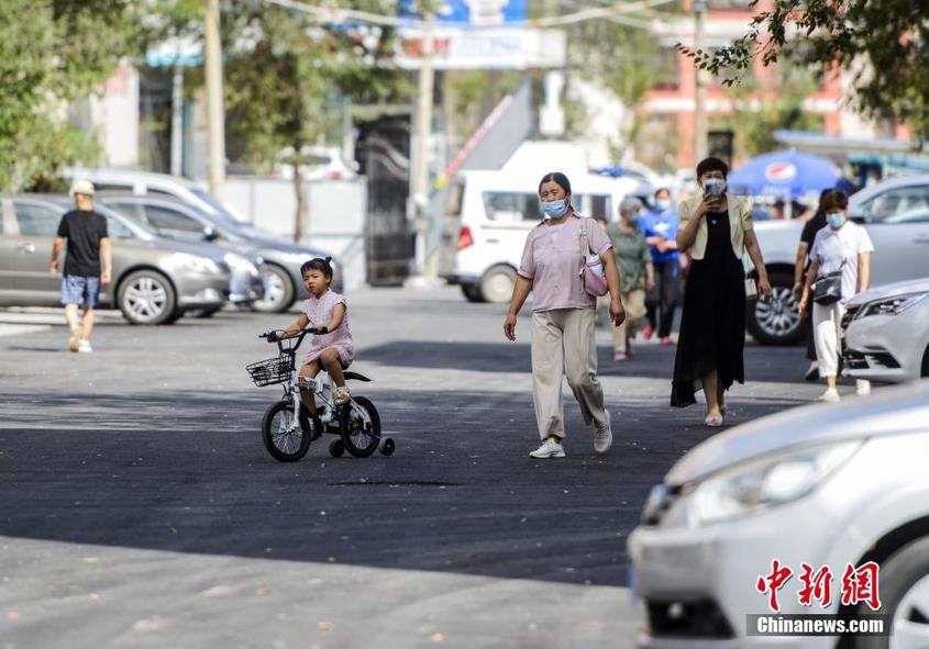 7月25日，新疆乌鲁木齐市沙依巴克区新通小区，外出居民走在刚刚完成硬化的小区道路上。中新社记者 刘新 摄