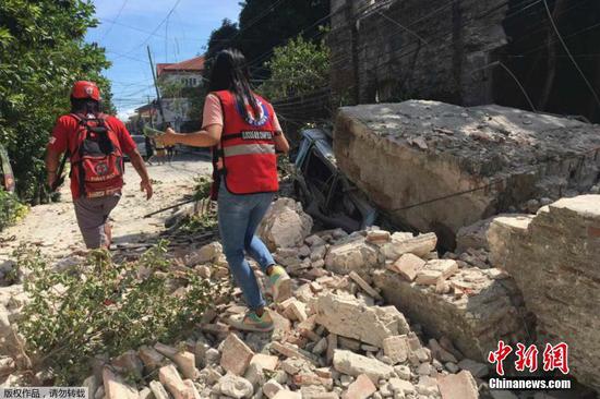 当地时间7月27日上午8点43分，菲律宾吕宋岛北部发生7.0级地震，尚无人员伤亡报告。菲首都马尼拉震感强烈。图为志愿者沿着坍塌的墙壁行走。