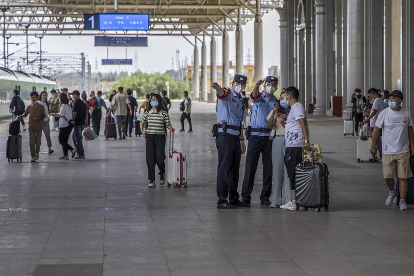 值乘伊犁至乌鲁木齐C842次“复兴号”城际列车乘警在伊宁站热心为旅客指引乘车方向。