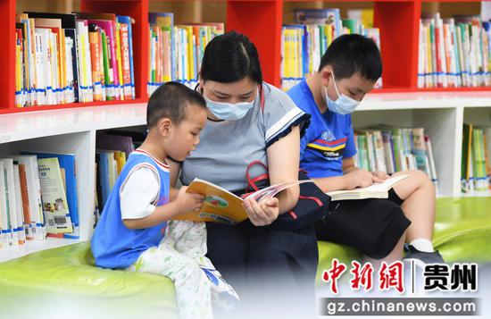 8月2日，在贵阳市南明区图书馆内的少儿阅读区，一名小朋友正在家人的陪同下阅读少儿图书。