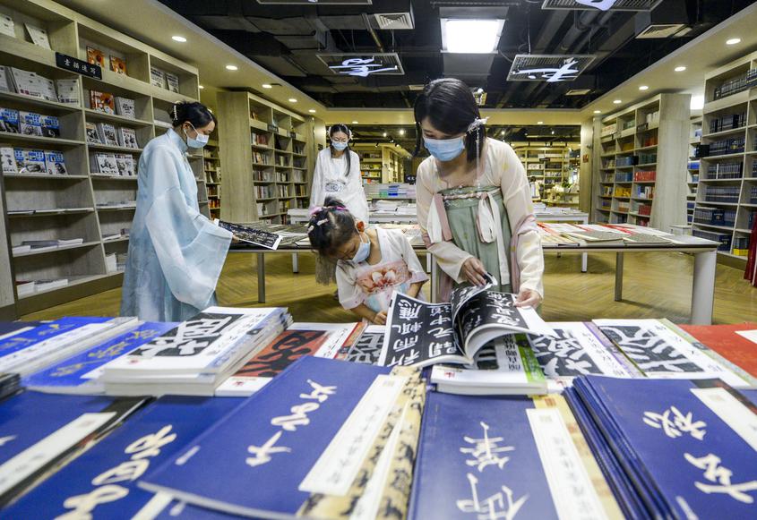 市民身着汉服在书城中选购传统文化书籍。