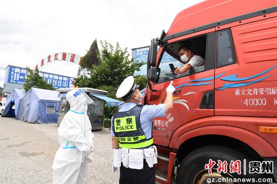 8月7日，交警及防疫人员在贵阳市南明区牛郎关高速路口防疫服务点查看入黔返黔大型货车司机的“双码”。