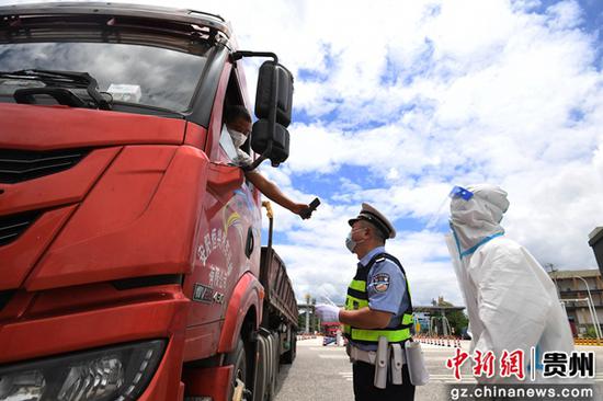 8月7日，交警及防疫人员在贵阳市南明区牛郎关高速路口防疫服务点查看入黔返黔大型货车司机的“双码”。