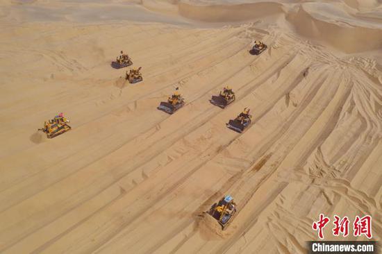 推土机和机械设备在被称为“死亡之海”的塔克拉玛干沙漠腹地施工。　项目部供图
