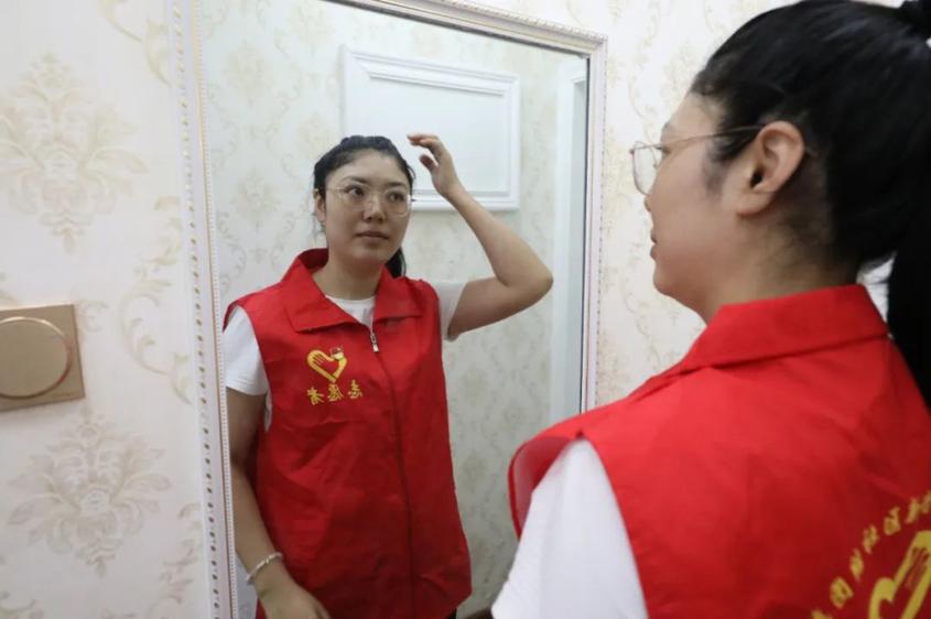 8月14日一大早，米克日阿依·库尔班洗漱收拾完，对着镜子整理衣装佩戴党员徽章。庞博 摄