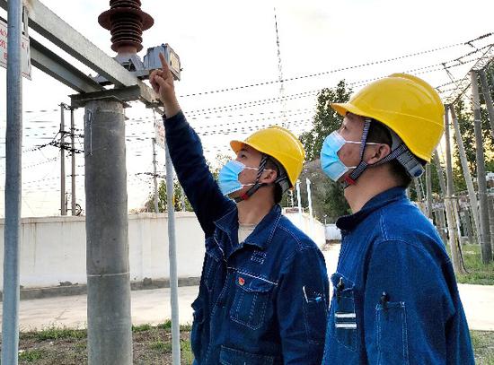 潘海鹏（左）正在110千伏明德变电站检查设备运行情况。赵夕彤 摄