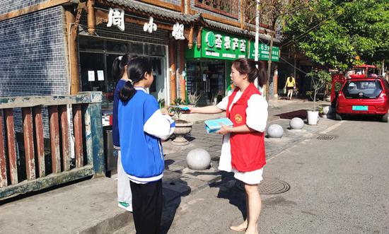 大方县雨冲乡志愿者向社区学生发放宣传手册。付芳 摄
