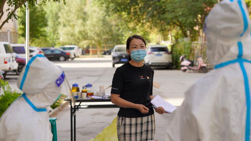 8月17日，在尉犁县尉犁镇金宇社区，社区党支部书记蔡伟芳在核酸检测点位与志愿者沟通工作细节。王雪 摄