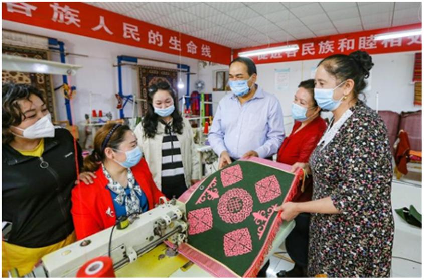 　　奇台县奇台镇犁铧尖社区卡尔湾箱包厂里，工人们正在讨论缝制布袋的细节。何龙 文/图

