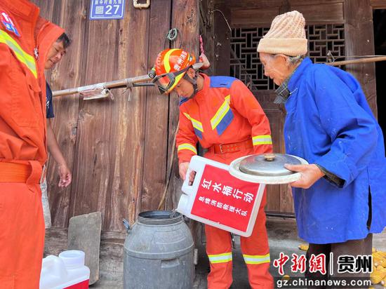 图为消防员将水送到村民家里。