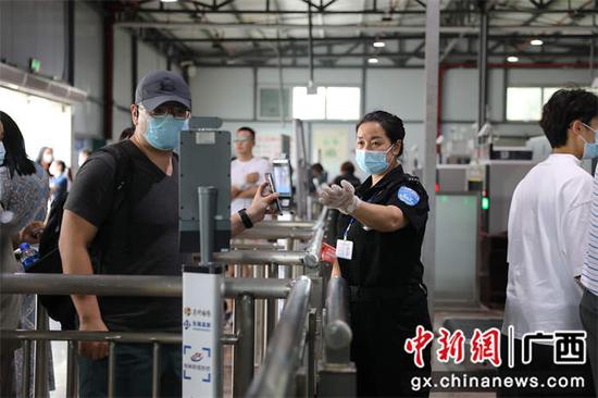 图为桂林北站安检人员引导旅客测量体温。李洪锐 摄